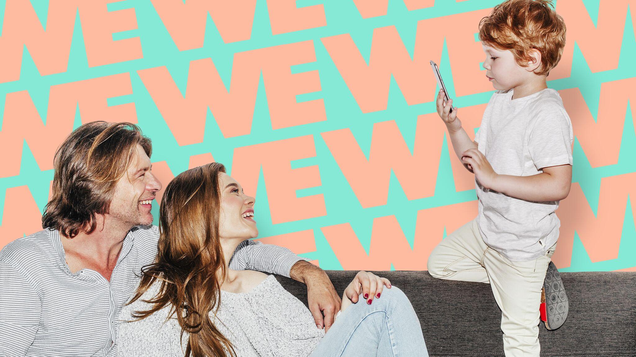 Parents on sofa dressed in white with small boy looking at mobile